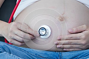 Portrait of Beautiful young pregnant women using stethoscope listening to her tummy.Pregnancy health care preparing for baby