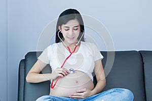 Portrait of Beautiful young pregnant women using stethoscope listening to her tummy.Pregnancy health care preparing for baby