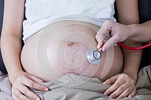 Portrait of Beautiful young pregnant women using stethoscope listening to her tummy.Pregnancy health care preparing for baby