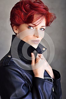 Portrait of a beautiful young red-haired woman with short hair in a leather jacket