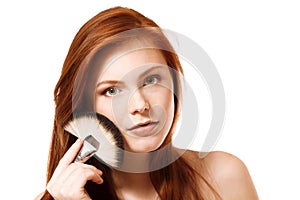 Portrait of beautiful young redheaded woman with makeup brush