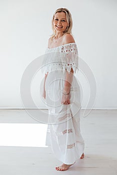 Portrait of a beautiful young slender woman in a white summer knitted dress