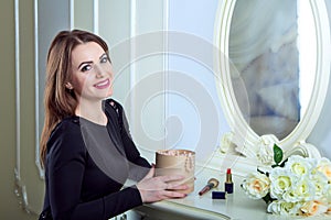Portrait of beautiful young smiling brunette woman sitting near mirror