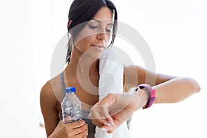 Beautiful young sporty woman looking her smartwatch at home.