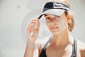 Portrait of a beautiful young sporty woman with visor cap in a warm day