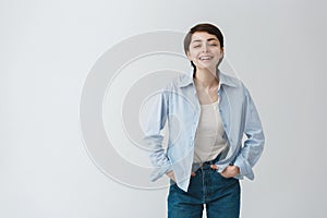 Portrait of beautiful young student girl with short dark hair in stylish casual clothes laughing with university friends