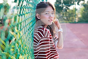 Portrait of beautiful young teen woman leaning steel net fence a