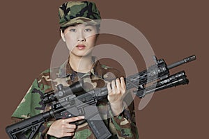 Portrait of beautiful young US Marine Corps soldier with M4 assault rifle over brown background