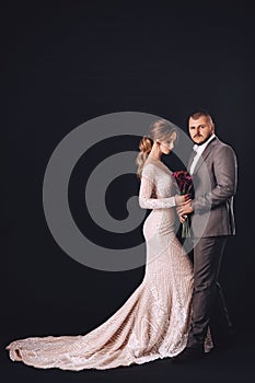 Portrait of beautiful young wedding couple at black background