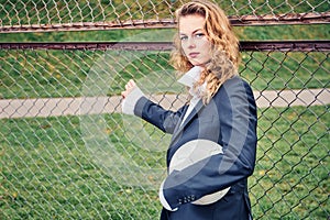 Portrait of beautiful young woman with ball near goal net at stadium