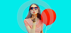 Portrait of beautiful young woman with balloon blowing her lips with lipstick sending sweet air kiss wearing red heart shaped