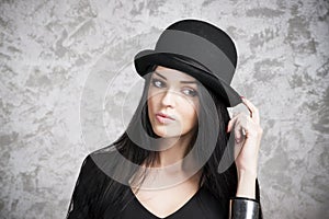 Portrait of a beautiful young woman in a black dress and bowler hat