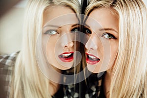 Portrait of beautiful young woman blonde girl and her reflection in mirror.