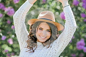 Portrait of a beautiful young woman in a blooming lilac park. Purple flowers. Spring. Happiness