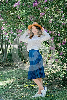 Portrait of a beautiful young woman in a blooming lilac park. Purple flowers. Spring. Happiness