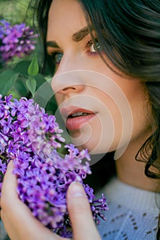 Portrait of a beautiful young woman in a blooming lilac park. Purple flowers. Spring. Happiness