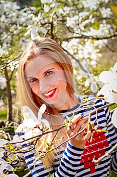 Portrait of beautiful young woman in blooming park on a sunny day. Smiling girl with Magnolia flowers