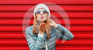 Portrait beautiful young woman blowing her red lips with red lipstick wearing a hat on colorful background