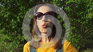 Portrait of a beautiful young woman blowing on the ripened dandelion