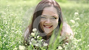 Portrait of a beautiful young woman blowing on the ripened dandelion in the park