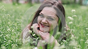 Portrait of a beautiful young woman blowing on the ripened dandelion in the park