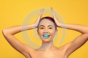 Portrait of beautiful young woman with bright make-up isolated on yellow studio background