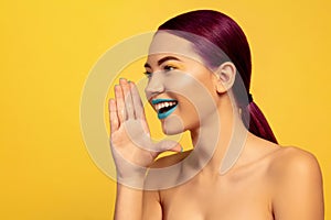 Portrait of beautiful young woman with bright make-up isolated on yellow studio background