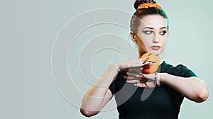 Portrait of a beautiful young woman with bun hairstyle and elegantly sandwiched orange fruit between hands,fashion portrait on