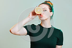 Portrait of a beautiful young woman with bun hairstyle and elegantly sandwiched orange fruit between hands,fashion portrait on