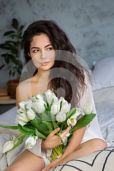 Portrait of a beautiful young woman with bunch of white tulips.