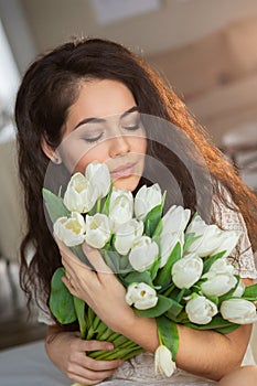 Portrait of a beautiful young woman with bunch of white tulips.