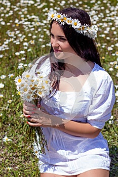 Portrait of a beautiful young woman in chamomile field. Happy girl collecting daisies. A girl resting in a field of chamomile. S