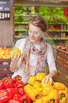 Portrait of beautiful young woman choosing vegetables in grocery