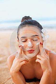 Portrait Of Beautiful Young Woman with Clean Fresh Skin touching face. Suntan Lotion. Sun Protection. Sun Cream.