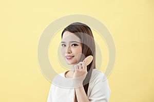 Portrait of beautiful young woman combing her hair and smiling