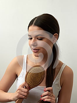 Portrait of beautiful young woman combing her hair on white background