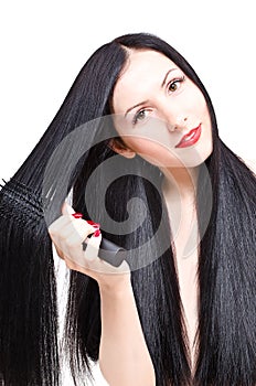 Portrait of a beautiful young woman combing her long groomed hair