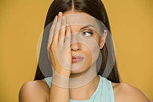 Portrait of beautiful young woman covering one eye with her palm