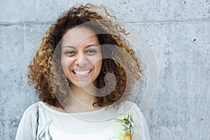 Portrait of a beautiful young woman with curly hair smiling outdoors