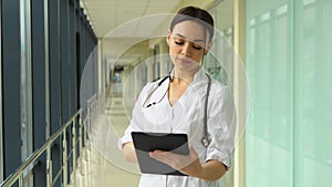 Portrait of beautiful young woman doctor holding digital tablet and looking at camera. Confident female doctor using