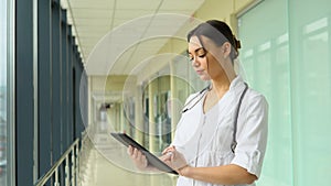 Portrait of beautiful young woman doctor holding digital tablet and looking at camera. Confident female doctor using