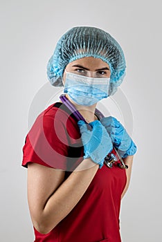 Portrait of beautiful young woman doctor wear red uniform, protective mask and rubber gloves