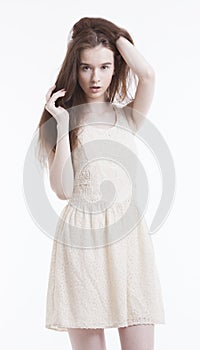 Portrait of beautiful young woman in dress with hand in her hair looking away against white background