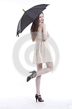 Portrait of beautiful young woman in dress with umbrella against white background