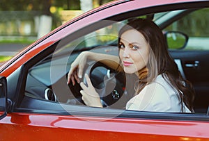 Portrait of beautiful young woman driver behind wheel red car