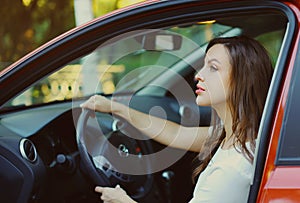 Portrait of beautiful young woman driver behind wheel red car