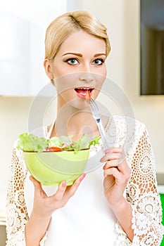 Portrait of a beautiful young woman eating vegetable salad