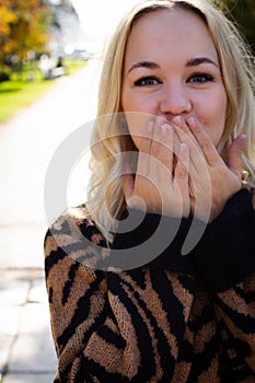 Portrait of a beautiful young woman enjoying autumn in the park. Attractive blonde in autumn park on a background of