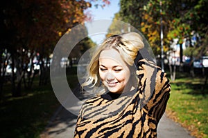 Portrait of a beautiful young woman enjoying autumn in the park. Attractive blonde in autumn park on a background of