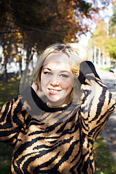 Portrait of a beautiful young woman enjoying autumn in the park. Attractive blonde in autumn park on a background of